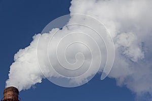 Thick white smoke comes from an industrial factory pipe into the sky. Ecology and atmosphere concept.