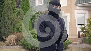 Thief in black clothes and balaclava before breaking into house. The guy going to steal things in rich house. Concept of