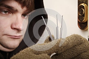Thief in black hoodie selecting one of plastic lockpick homemade tools