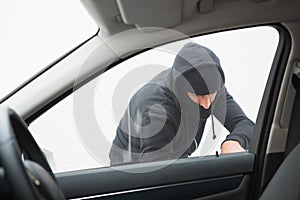 Thief breaking into car with screwdriver