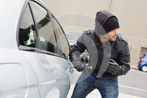 Thief breaking into car with screwdriver