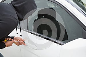 Thief breaking into car with screwdriver