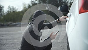 Thief breaking in car using mobile phone