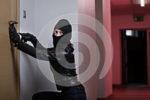 Thief broke into the apartment. House robbery by woman in a black jacket and black mask. Burglar in a mask. Thief in a mask