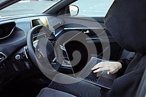 Thief hacking car system with laptop inside vehicle, closeup