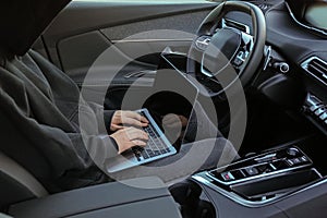 Thief hacking car system with laptop inside vehicle, closeup