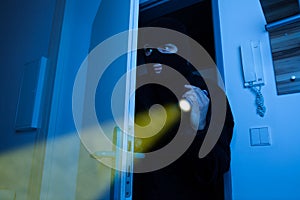 Thief holding flashlight while entering into house photo