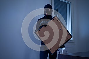 Thief inside home stealing a painting
