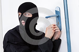 Thief opening door with tool during house breaking