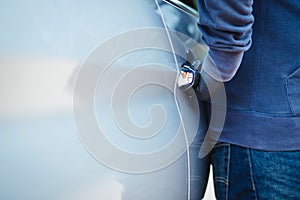 The thief opens the car door to get him into the car.