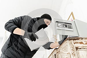 The thief opens the electronic safe. The burglar commits a crime in Luxury apartment with stucco. Thief with black