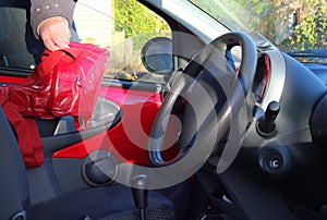 Thief stealing a handbag from a vehicle or automobile.