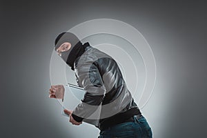 Thief stealing a laptop computer. Isolated on gray background