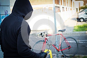 Thief stealing a parked bike in city street