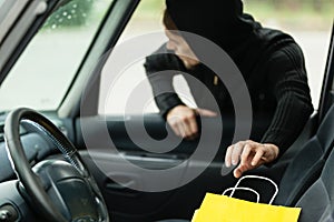 Thief stealing shopping bag from the car