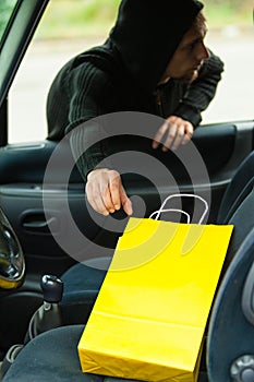Thief stealing shopping bag from the car