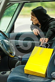 Thief stealing shopping bag from the car