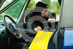 Thief stealing shopping bag from the car