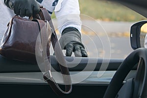 The thief steals a bag with documents through a window of the car, left by the owner