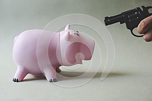 Pink piggy bank and hand with gun