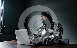 Thief use computer for theft. Hacker stealing data from a laptop concept for network and computer crime