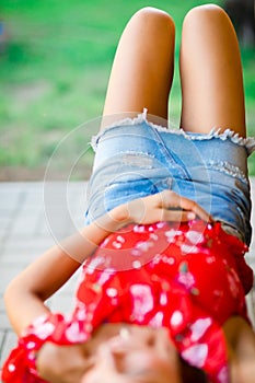 Thigh of girl in short jeans skirt lying