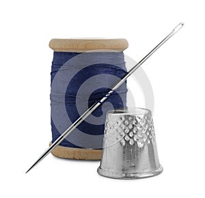 Thimble and spool of blue sewing thread with needle isolated on white