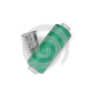 Thimble and spool of green sewing thread isolated on white, top view