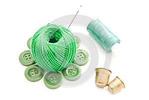 Thimbles, needles and green thread on white