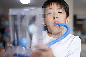 Thin boy uses a Tri-ball Incentive Spirometer for check his lung function