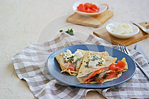 Thin crepe pancakes with salted salmon and cream cheese on a gray plate on a light concrete background photo
