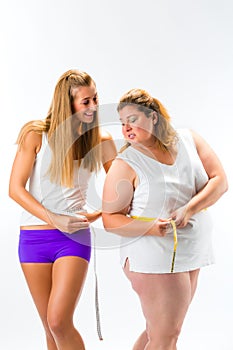 Thin and fat woman measuring waist with tape photo