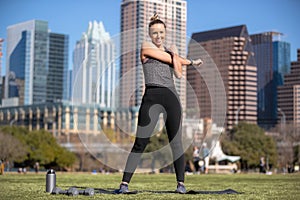 Thin, fit, toned woman in sportswear with muscular legs practicing exercise routine in downtown city park