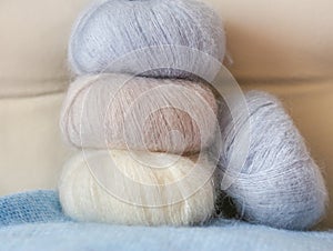 Thin fluffy skeins of wool for knitting a pale pink, blue and be
