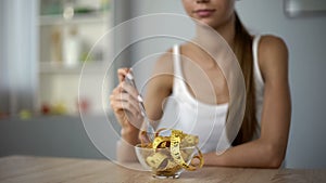 Thin girl eating measuring tape, concept of calorie counting, body mass index