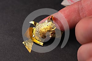 Thin gold foil on male finger. Pure gold