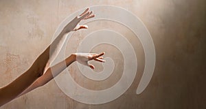 Thin graceful dancing hands of ballerina on wall background