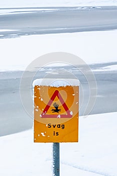 Thin ice warning sign by a lake