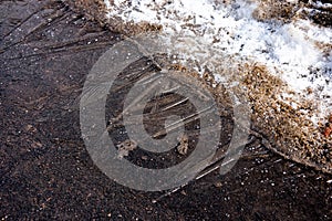 Thin layer of ice on the asphalt and dirty snow close