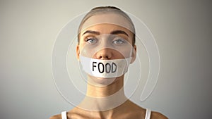 Thin model with taped mouth, concept of food restriction and anorexia, diet