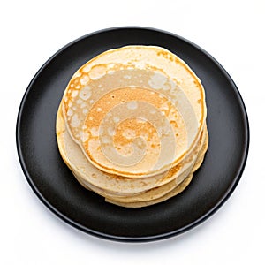 Thin pancakes on a black plate isolated on white background
