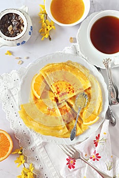 Thin pancakes blinis in orange sauce and cup of black tea