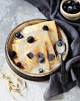 Thin pancakes with blueberries and condensed milk on a plate