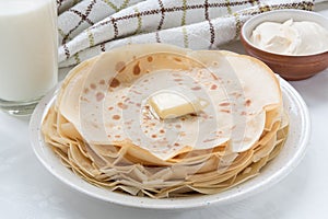 Thin pancakes with butter on white plate