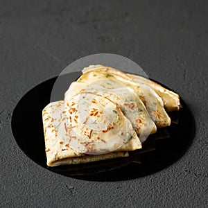 Thin pancakes with dill on gray background. Simple crepes with herbs or greens. Baking food. Soft focus