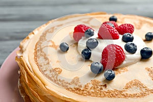 Thin pancakes served with cream and berries