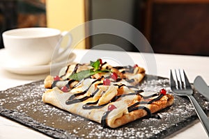 Thin pancakes served with sauce and berries on slate plate