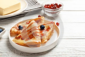 Thin pancakes served with syrup and berries