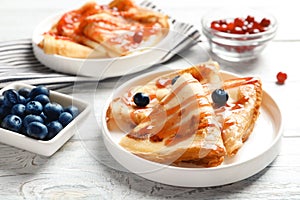 Thin pancakes served with syrup and berries