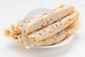 Thin pancakes on white plate.